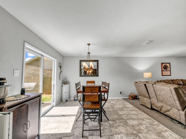 dining area featuring a chandelier, light colored carpet, visible vents, and baseboards