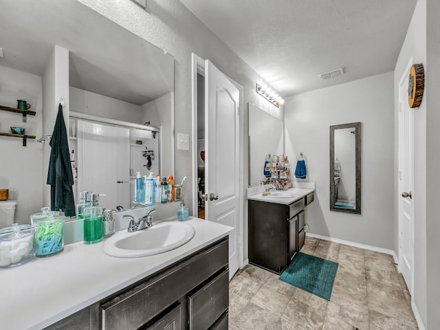 full bathroom with a stall shower, vanity, visible vents, and baseboards