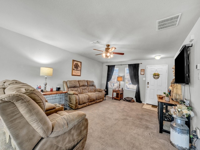 living room featuring light carpet, visible vents, and a ceiling fan