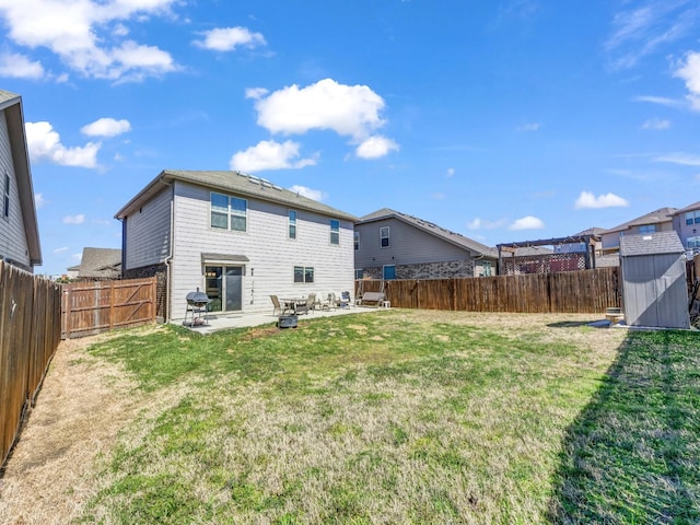 back of property with an outbuilding, a patio, a lawn, a storage shed, and a fenced backyard