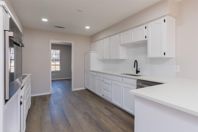 kitchen featuring visible vents, dark wood-style flooring, stainless steel appliances, a sink, and white cabinets