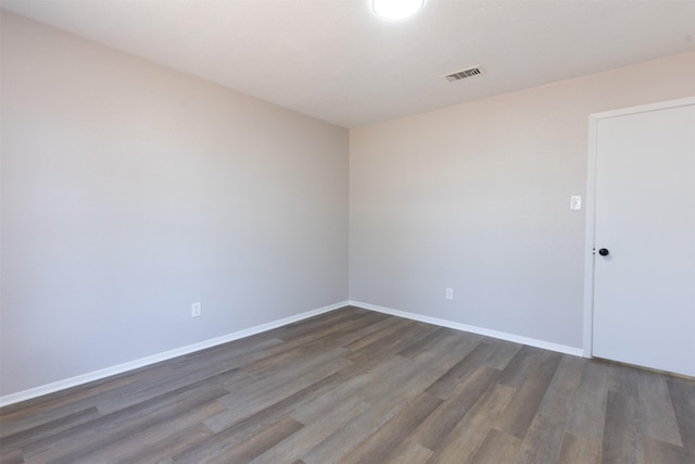 spare room featuring wood finished floors, visible vents, and baseboards