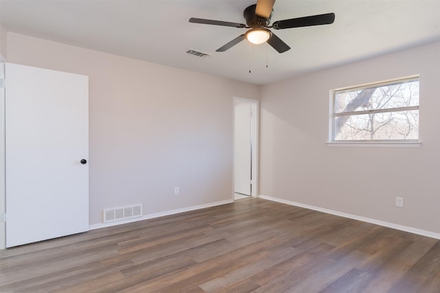 spare room with visible vents, baseboards, and wood finished floors