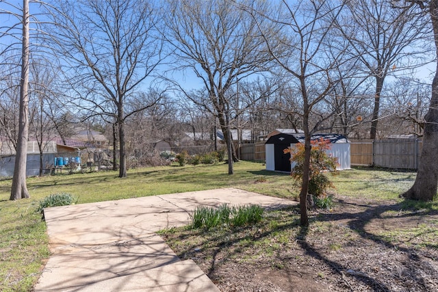 view of yard featuring a storage shed, an outbuilding, and fence