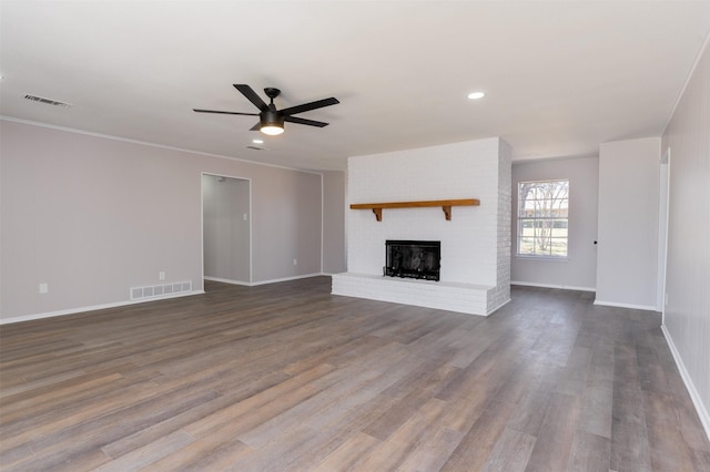 unfurnished living room featuring dark wood-style floors, visible vents, a brick fireplace, and ceiling fan