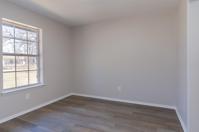 spare room featuring baseboards, a healthy amount of sunlight, and dark wood-style floors