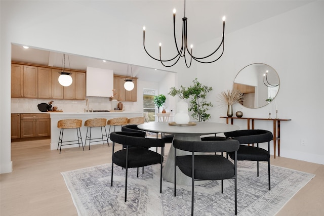 dining area featuring baseboards, light wood finished floors, a towering ceiling, and recessed lighting