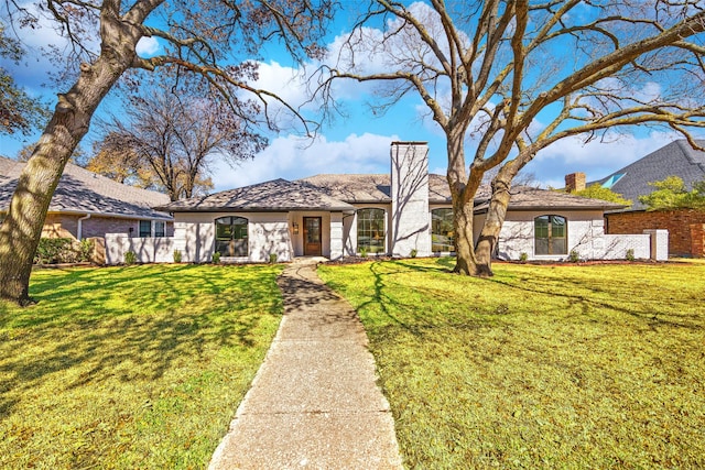 view of front of house featuring a front lawn, a chimney, and fence