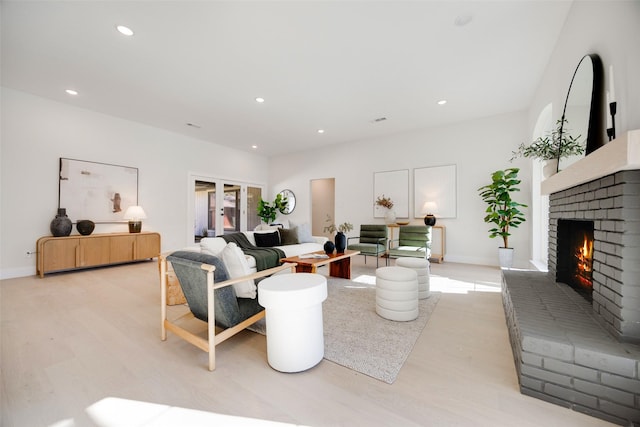 living area with recessed lighting, a brick fireplace, light wood-style flooring, and baseboards