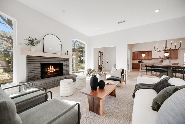 living area featuring recessed lighting, a brick fireplace, visible vents, and an inviting chandelier