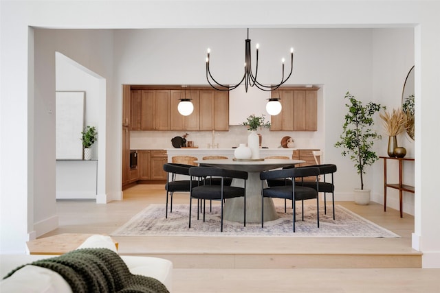 kitchen with pendant lighting, a notable chandelier, light countertops, light wood finished floors, and tasteful backsplash