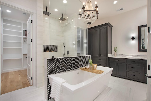 bathroom with a walk in closet, visible vents, built in shelves, a soaking tub, and a tile shower