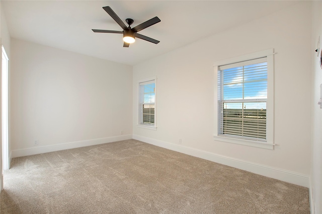 carpeted empty room featuring a ceiling fan and baseboards