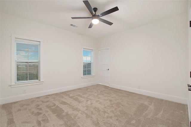 carpeted spare room with visible vents, baseboards, and ceiling fan