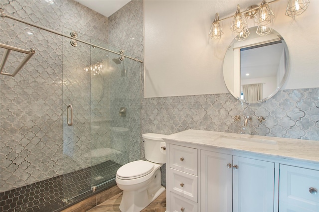 bathroom featuring tile walls, toilet, a stall shower, and vanity