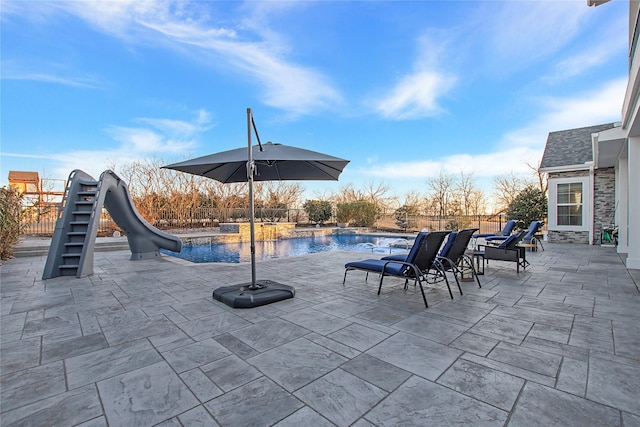 view of swimming pool with a water slide, ceiling fan, a pool with connected hot tub, and a patio
