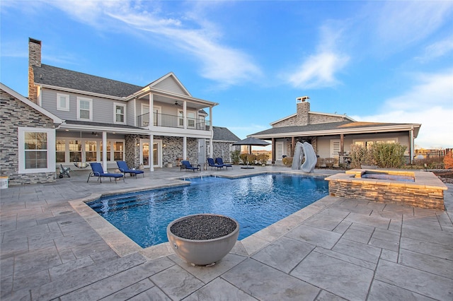 view of pool featuring a pool with connected hot tub, ceiling fan, a patio, and a water slide