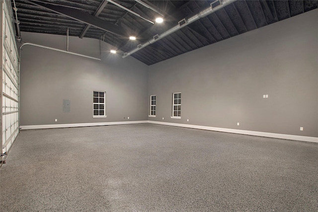 unfurnished room with baseboards and high vaulted ceiling