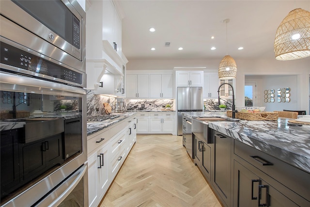 kitchen featuring stone counters, stainless steel appliances, white cabinets, and a sink