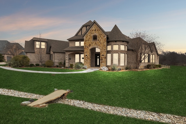 view of front of home featuring a front yard, brick siding, and stone siding