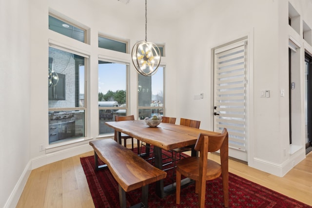 dining area featuring a notable chandelier, baseboards, and light wood-style floors