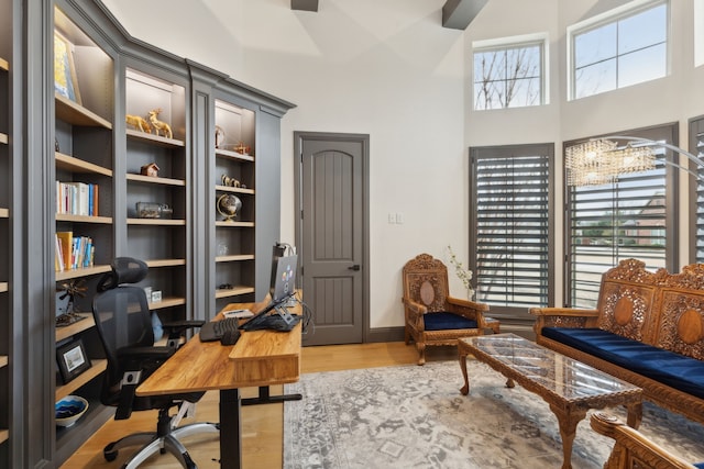 office area with a towering ceiling and light wood finished floors