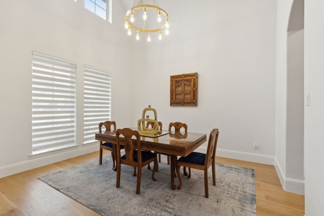 dining area with light wood finished floors, baseboards, and a towering ceiling