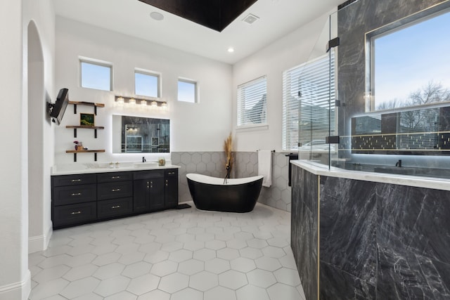 bathroom with walk in shower, a freestanding bath, tile walls, and vanity