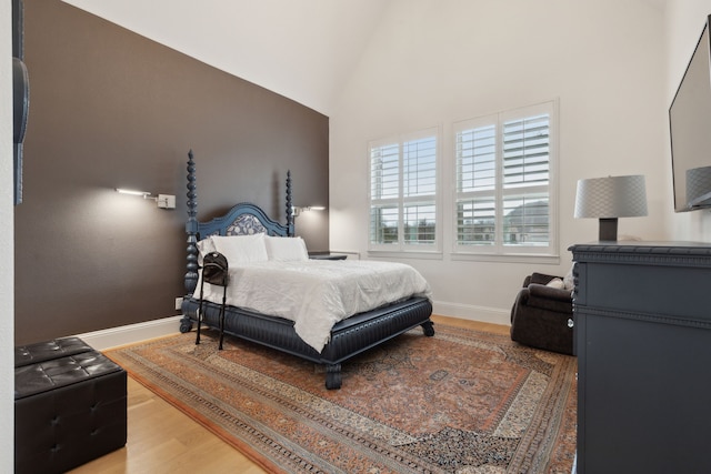 bedroom with lofted ceiling, light wood-style flooring, and baseboards