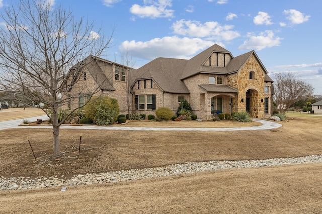 view of front of house featuring brick siding, stone siding, and a shingled roof