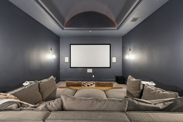 carpeted cinema room featuring a tray ceiling, visible vents, and a textured wall