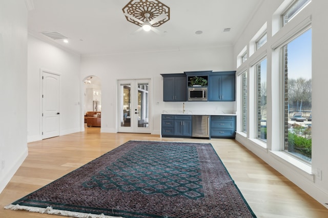 living room featuring baseboards, visible vents, arched walkways, french doors, and light wood-type flooring