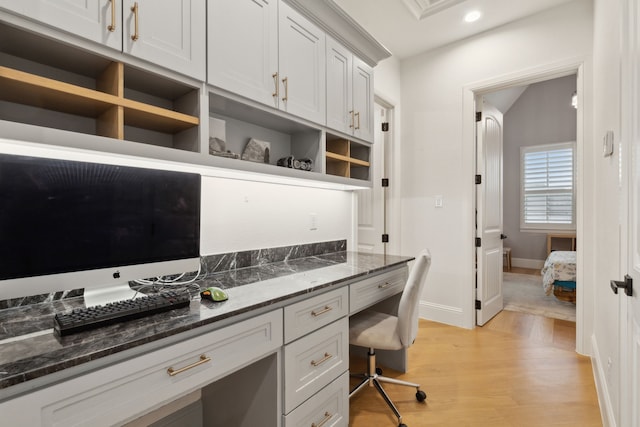 office featuring baseboards, recessed lighting, vaulted ceiling, built in desk, and light wood-type flooring