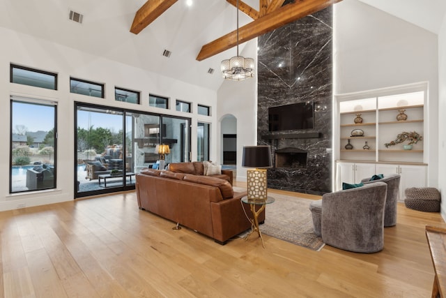 living room featuring visible vents, high vaulted ceiling, beam ceiling, a fireplace, and light wood-style floors