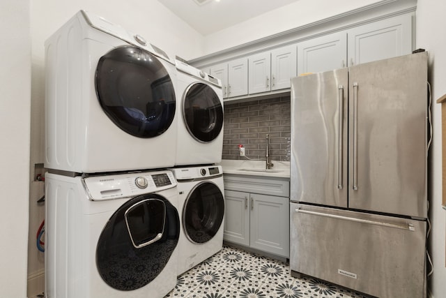 laundry area featuring laundry area, light floors, stacked washer / drying machine, and a sink