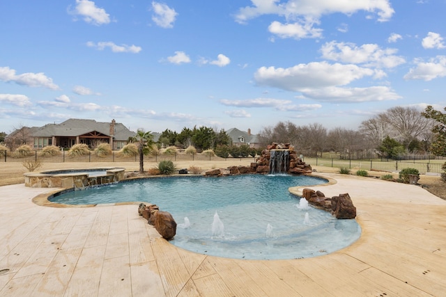 view of swimming pool with fence and a pool with connected hot tub