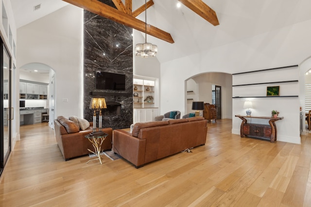 living area with visible vents, high vaulted ceiling, arched walkways, a fireplace, and light wood finished floors