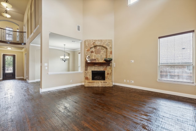 unfurnished living room with plenty of natural light, dark wood finished floors, a fireplace, and a high ceiling