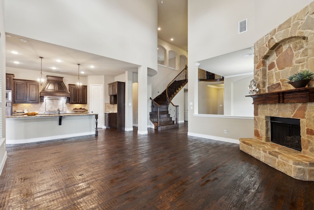 unfurnished living room with baseboards, visible vents, stairway, dark wood-type flooring, and a fireplace