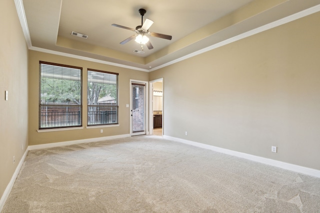 unfurnished room featuring light colored carpet, visible vents, baseboards, ornamental molding, and a tray ceiling