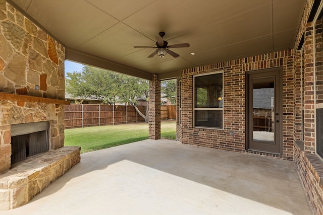 view of patio / terrace featuring ceiling fan, an outdoor stone fireplace, and fence