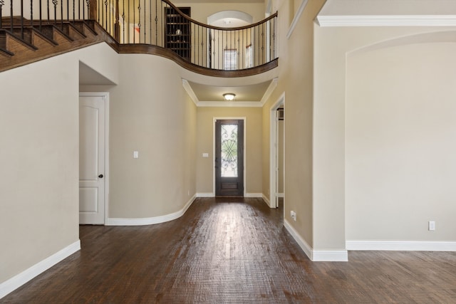 foyer entrance featuring a towering ceiling, baseboards, and wood finished floors