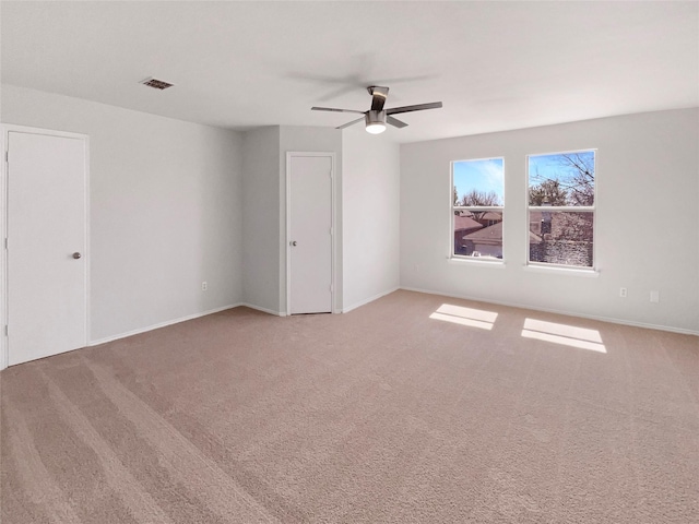 carpeted spare room with visible vents, ceiling fan, and baseboards