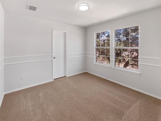 carpeted spare room featuring visible vents and baseboards