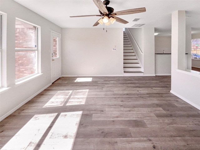 empty room with visible vents, stairway, a ceiling fan, wood finished floors, and baseboards