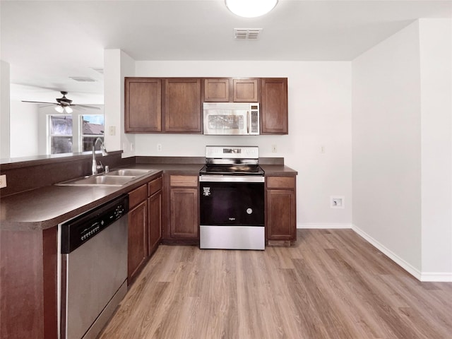 kitchen featuring dark countertops, visible vents, appliances with stainless steel finishes, light wood-style floors, and a sink