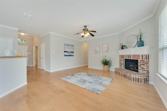 living area featuring ceiling fan, light wood-style flooring, a fireplace, baseboards, and ornamental molding