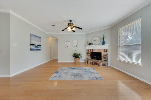 living room featuring a brick fireplace, light wood-style flooring, visible vents, and ornamental molding