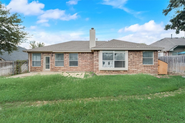 rear view of property with brick siding, a yard, a chimney, and a fenced backyard