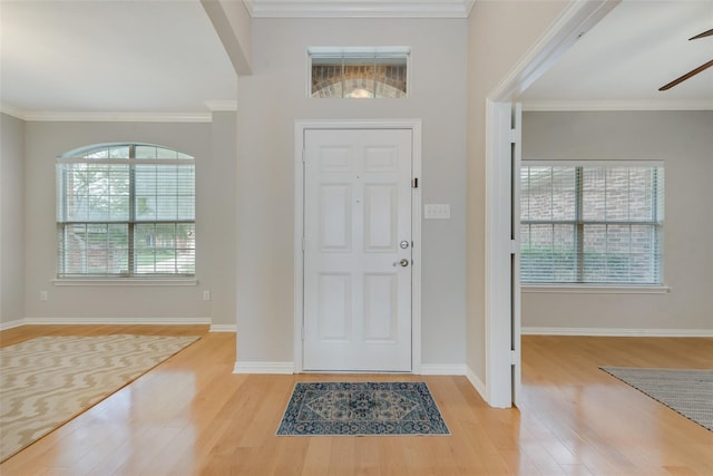 entrance foyer featuring ornamental molding, light wood-type flooring, ceiling fan, and baseboards